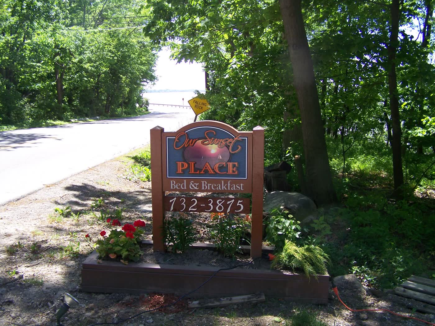 The Our Sunset Place Bed & Breakfast sign on East Sand Road, with the lake beyond